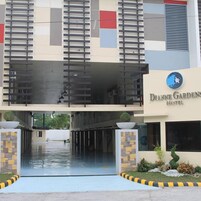 A hotel entrance with a modern design, featuring a flat roof, a covered walkway, and a sign for Dianne Gardens Hotel.