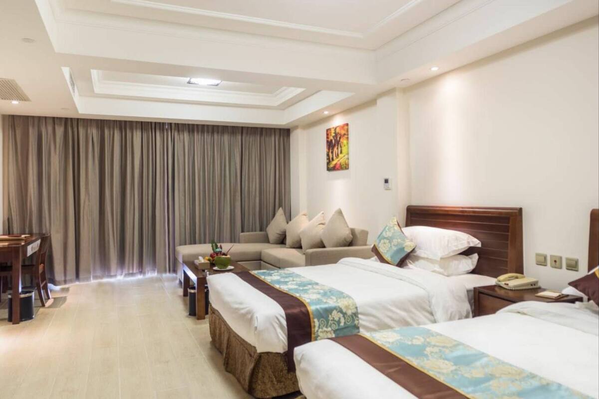 Ein Hotelzimmer mit einem großen Bett, einer Couch, einem Schreibtisch und einem Vorhang.