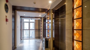 A modern hotel lobby with a geometric patterned wall, a marble floor, and a view of the city through a glass door. - Sanya Baohong Shang Haihuating boutique hotel (Sanya)