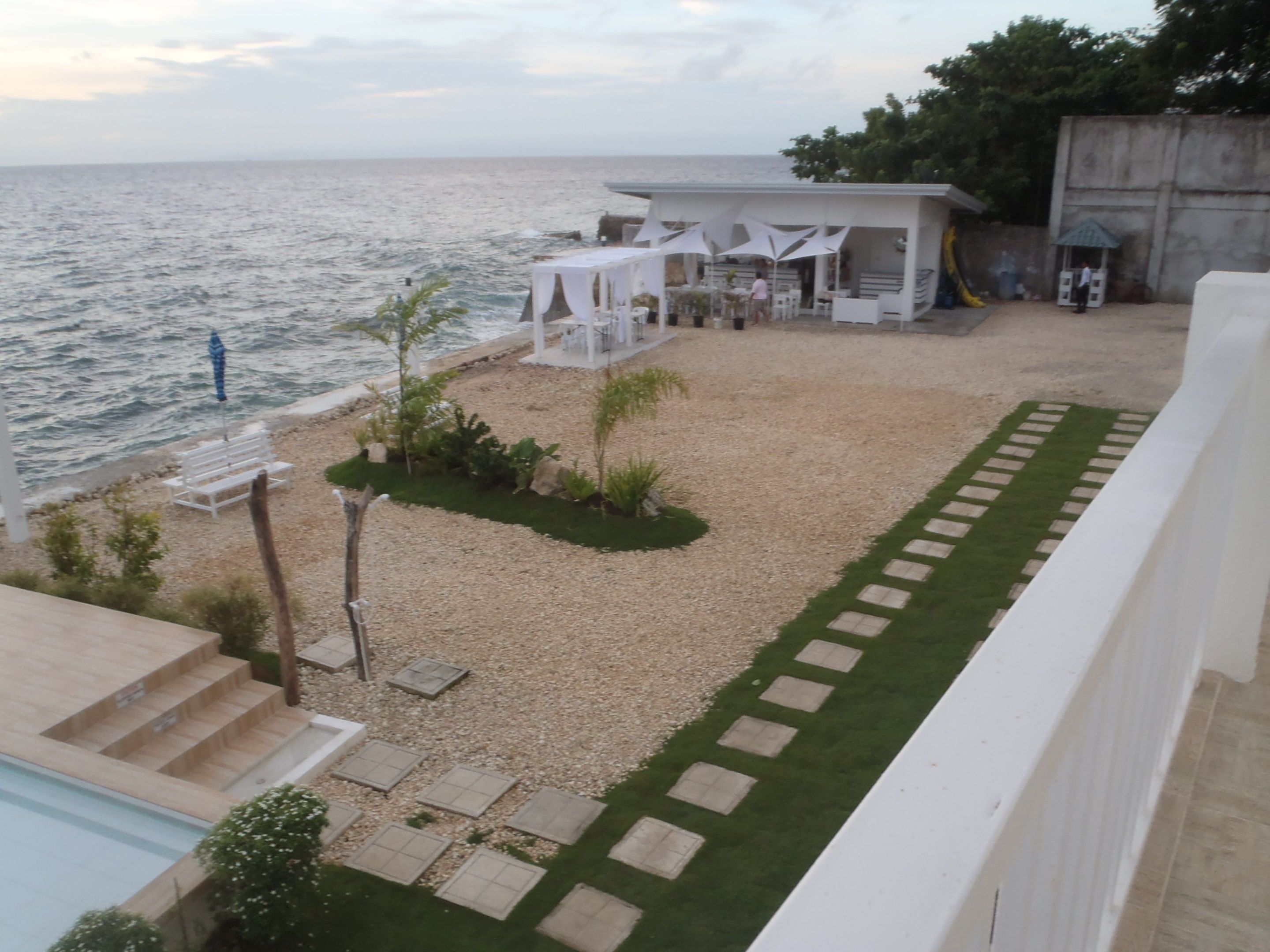 Eine Strandterrasse mit Pool, überdachter Sitzgruppe und Meerblick.