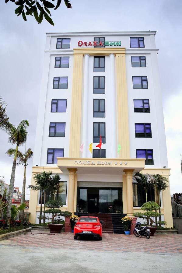 OSAKA Hotel features a symmetrical facade with a central entrance and palm trees.