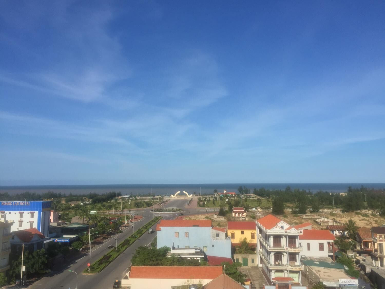 Ein Hotel mit Blick auf das Meer, eine Kreisverkehr und eine Mischung aus Wohngebäuden.