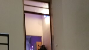 Ein Durchgang zu einem Zimmer mit Bett, Stuhl und Tisch.