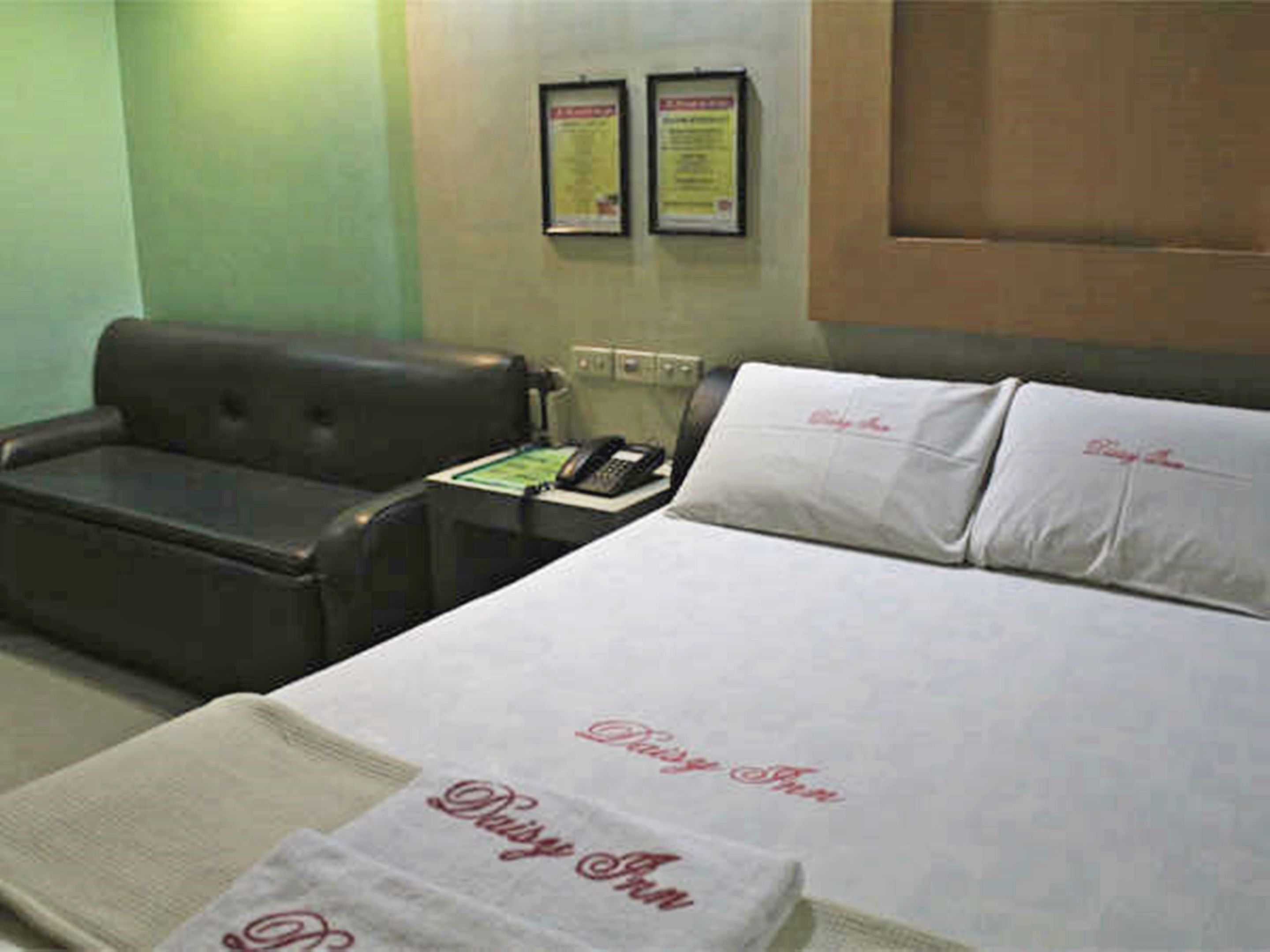 Una habitación de hotel con una cama, una silla, un teléfono y dos carteles enmarcados en la pared.