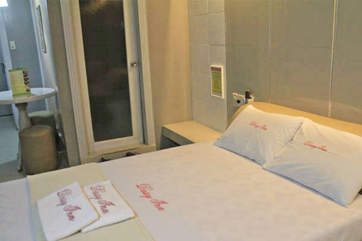 A hotel room with a bed, a bedside table, and a shower area.