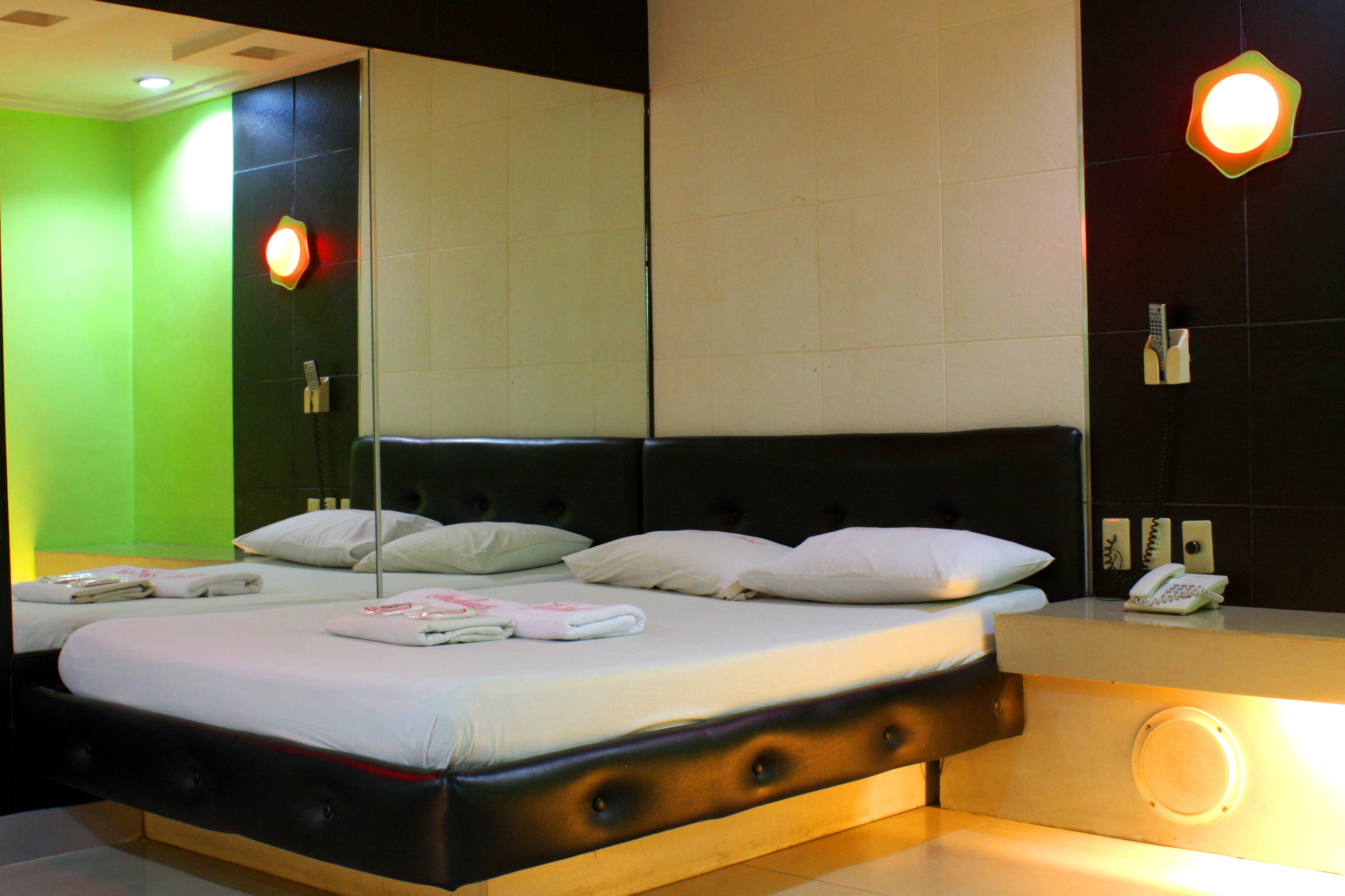 Une chambre d’hôtel avec un grand lit, une table de chevet, un miroir et un téléphone fixé au mur.