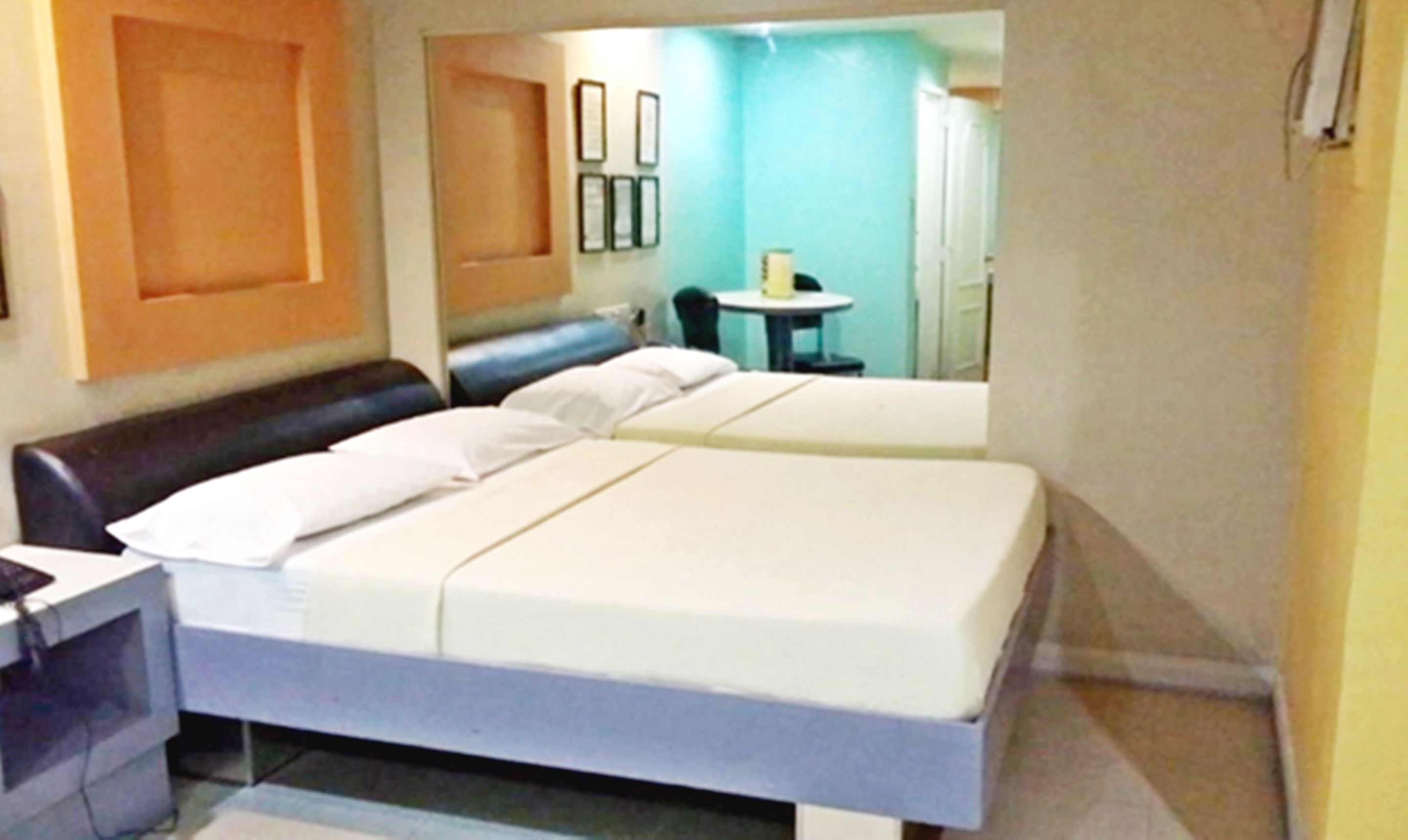Ein Hotelzimmer mit zwei Betten, einem Schreibtisch, einem Stuhl und einem kleinen Tisch.