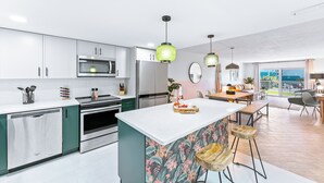 Een moderne keuken met witte kasten, roestvrijstalen apparatuur en een centraal kookeiland met krukken.