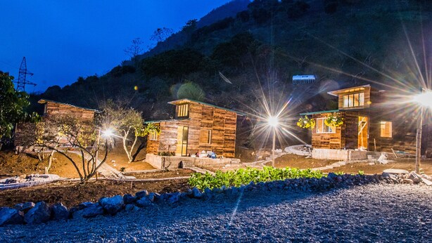 Una cabaña rústica con fachada de piedra, un pequeño porche y un interior bien iluminado.