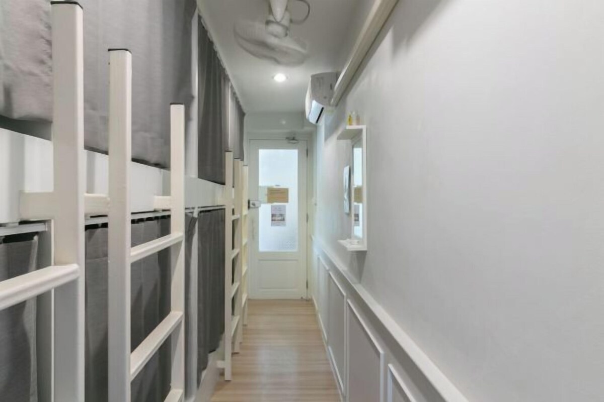 A narrow hallway with white walls and a wooden floor.