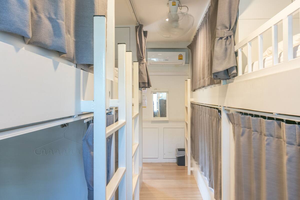 Un couloir étroit avec un ventilateur de plafond, une fenêtre et une porte au fond.