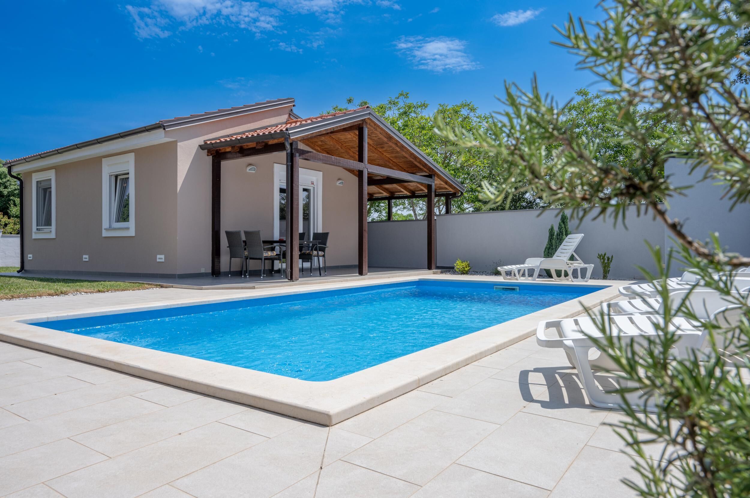 Une maison moderne dotée d’une piscine, d’un espace salon extérieur et d’une pergola.