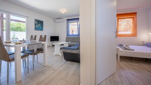 A modern living room with a dining area, a sofa, a TV, and a bed.