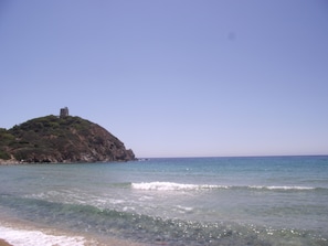 A coastal scene with a rocky island featuring a tower.