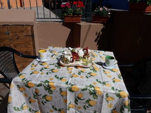 Ein Tisch ist gedeckt mit einer Tischdecke mit Zitronenmuster, einem Teekessel, Tassen und einer Schale mit Blumen.