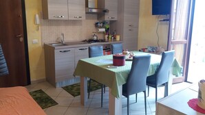 A compact kitchen with a dining area, a single bed, and a view of the outside. - Sole&Cuore is an elegant apartment accessorized and close to the beautiful CHIA   (Domus De Maria)