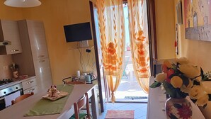 A kitchen with a stove, oven, and a flat-screen TV mounted on the wall. - Sole&Cuore is an elegant apartment accessorized and close to the beautiful CHIA   (Domus De Maria)