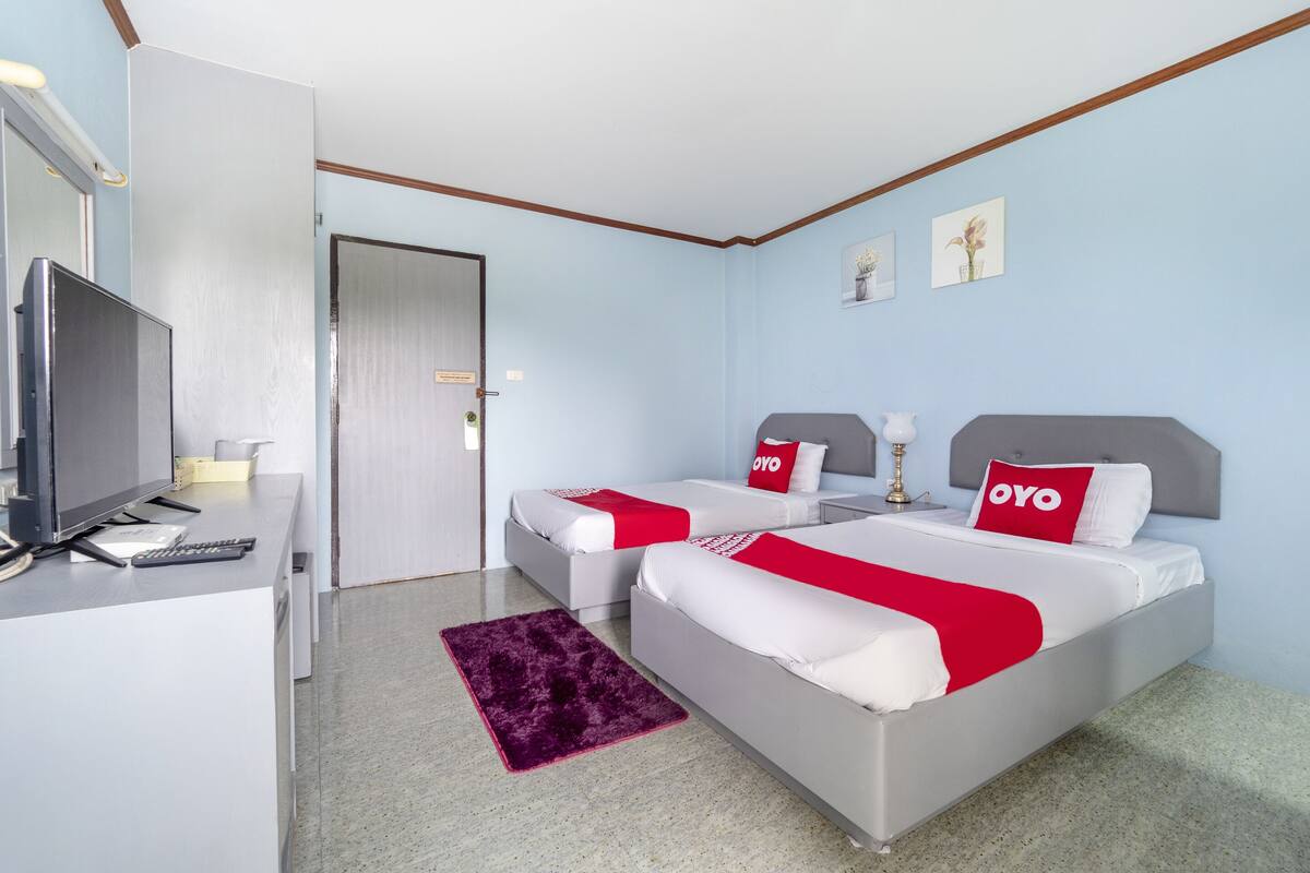 Une chambre d’hôtel avec deux lits, un bureau, une télévision et une porte.
