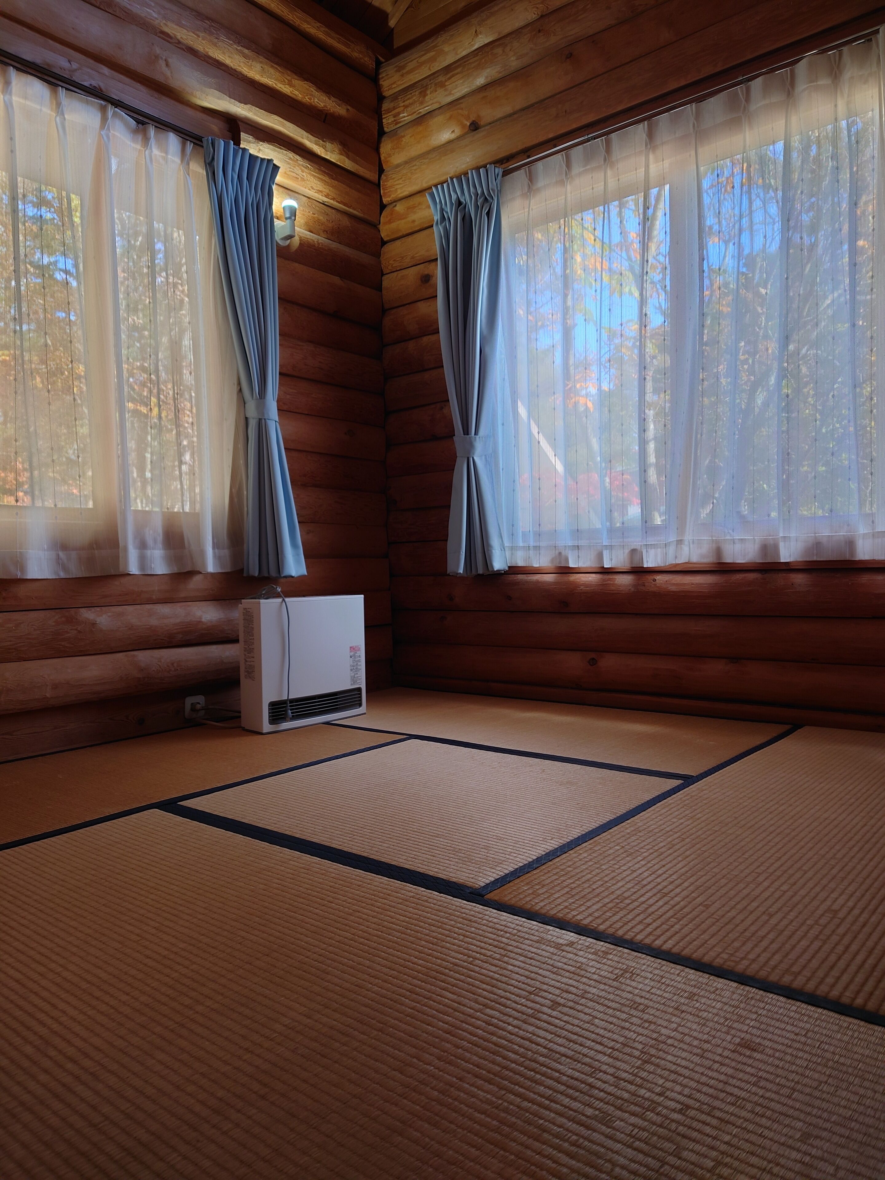 A room with wooden walls, tatami mats, and a heater.