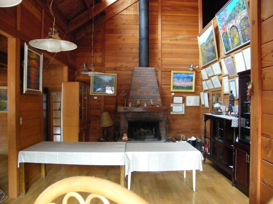 Un acogedor interior de cabaña con chimenea, paredes de madera y obras de arte enmarcadas.