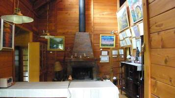 A rustic wooden interior with a fireplace, framed pictures, and a table set for dining.