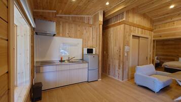 Una cocina compacta con paredes de madera, un microondas y un lavabo.