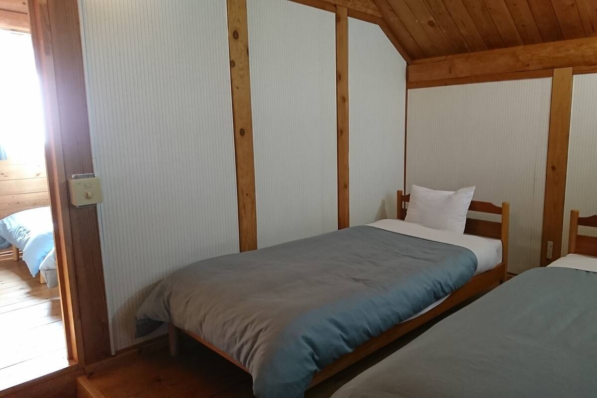 Ein Zimmer mit zwei Betten, Holzwänden und einer Holzbalkendecke.