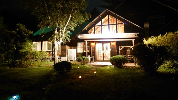 Ein zweistöckiges Haus mit einer großen Veranda und einem überdachten Sitzbereich im Freien.