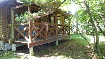 A wooden cabin with a porch and a covered deck area.