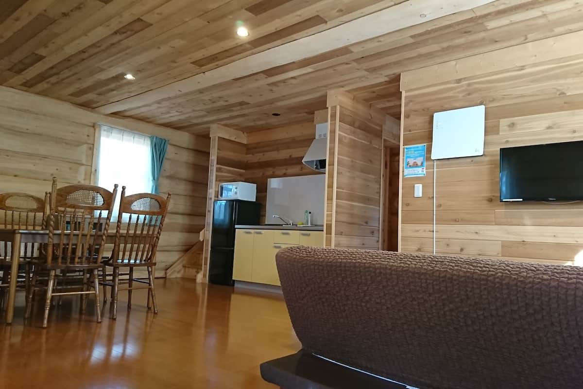 Ein Holzinnenraum mit Essbereich, Küche und einem an der Wand montierten Fernseher.