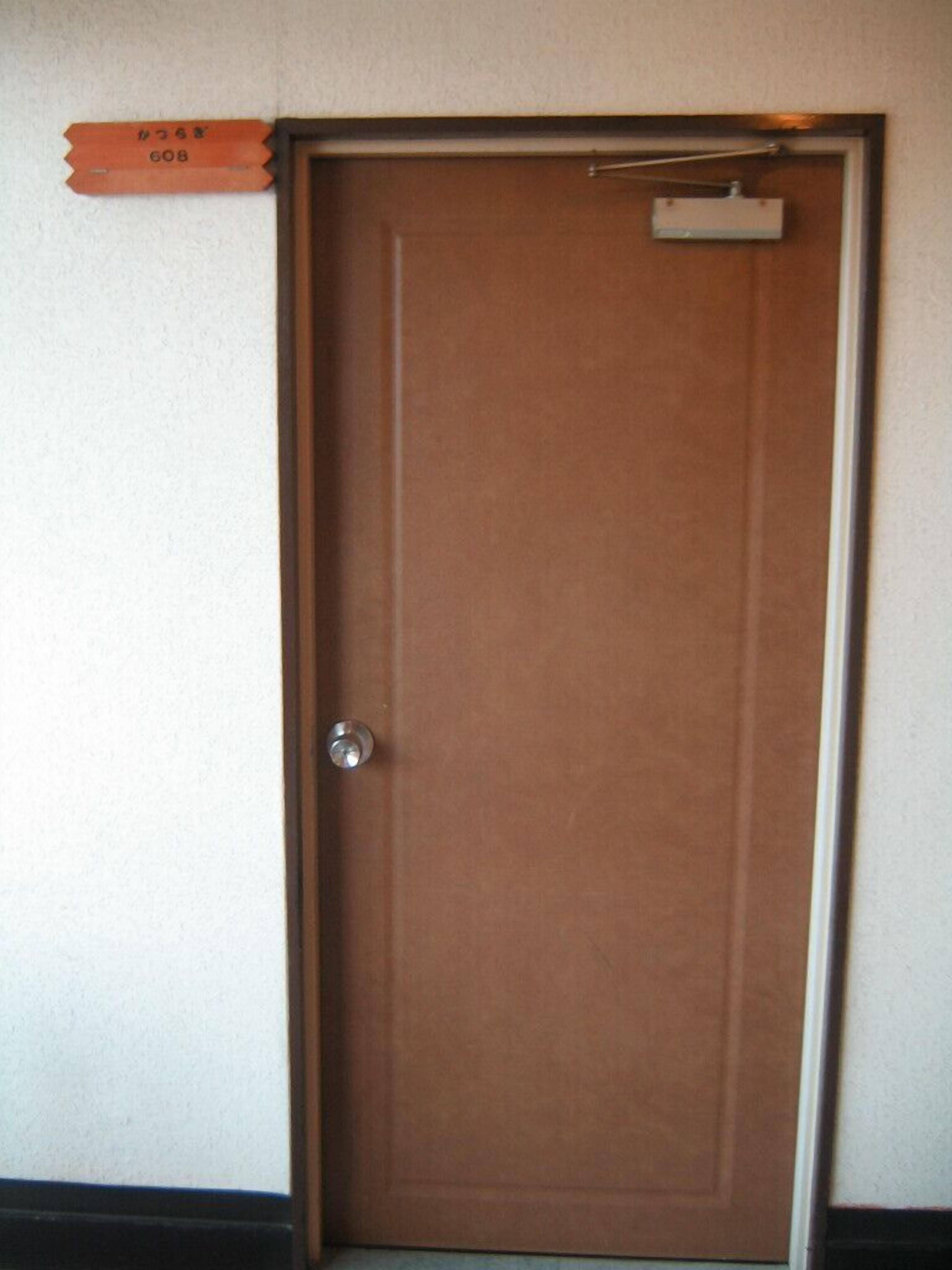 A closed wooden door with a metal handle and a small sign above it.