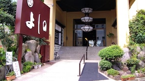 A building entrance with a ramp, potted plants, and a bicycle parked outside. - Hotel Yoshino (Ito)