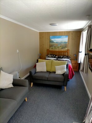 Ein Zimmer mit einem Bett, einem Schlafsofa, einem Heizkörper und einem Bild an der Wand.