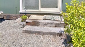 Un petit bâtiment d’un seul étage, à l’extérieur vert, doté d’une porte-fenêtre coulissante et d’un petit porche.