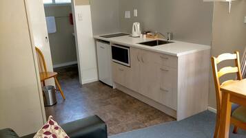 Un espacio habitable compacto con kitchenette, un sofá, zona de comedor y televisor.