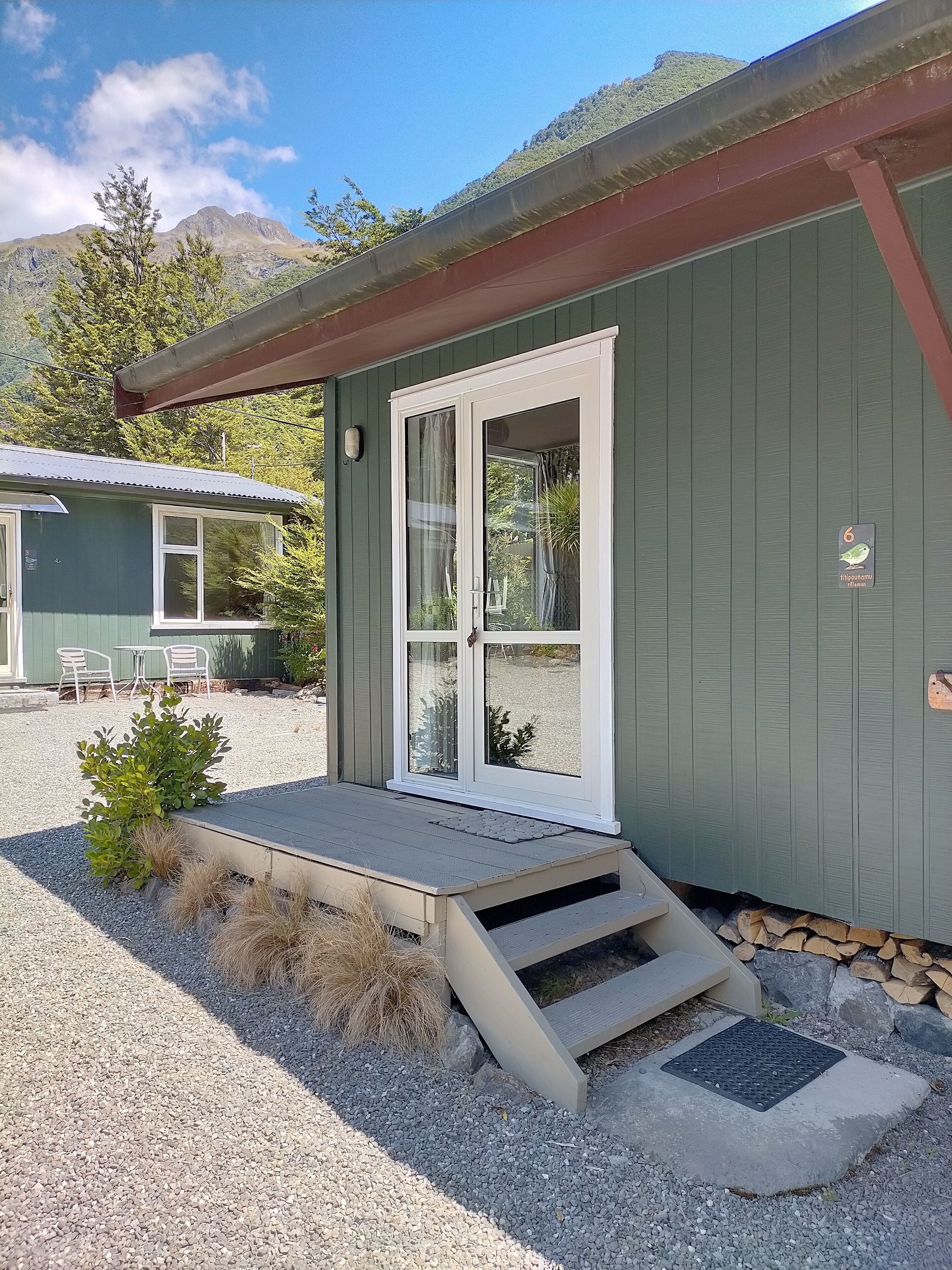 A small, single-story building with a green exterior and a white door.