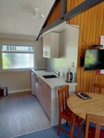 Cocina compacta con un lavamanos, una tetera y un televisor montado en la pared.