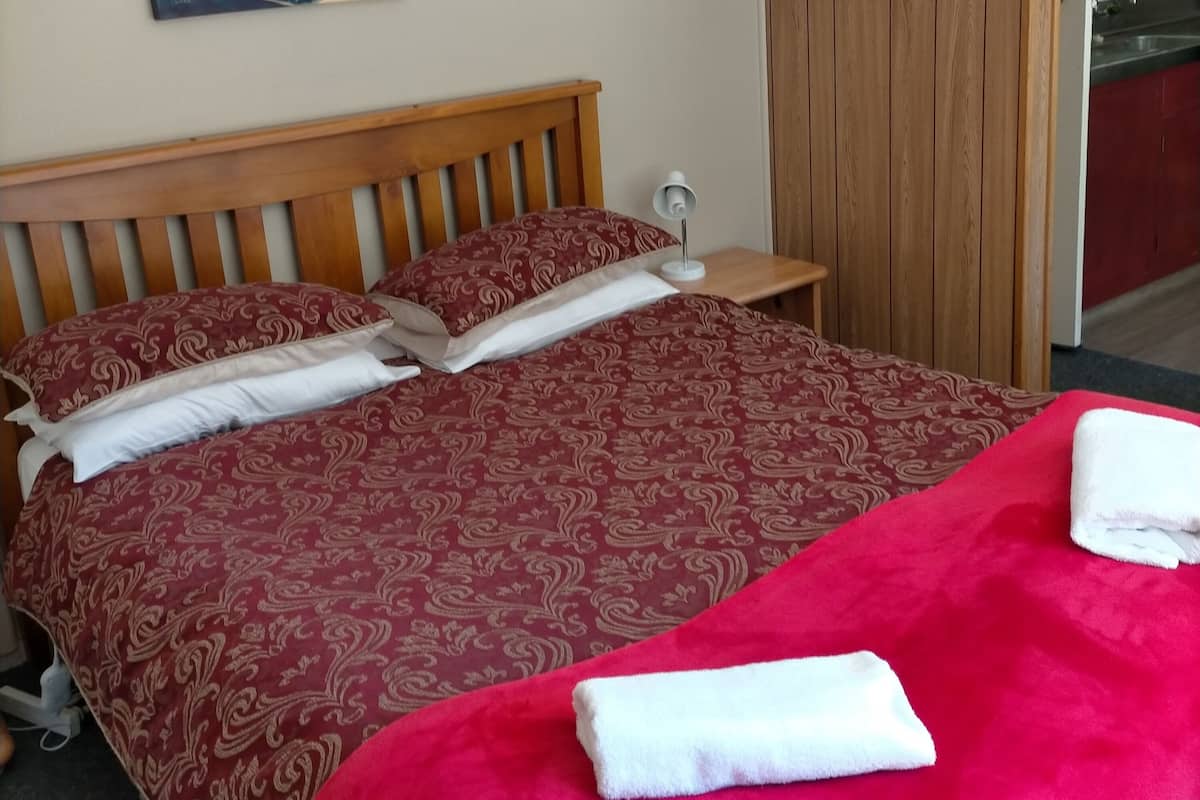 Een hotelkamer met een groot bed, een schilderij aan de muur en een houten garderobe.