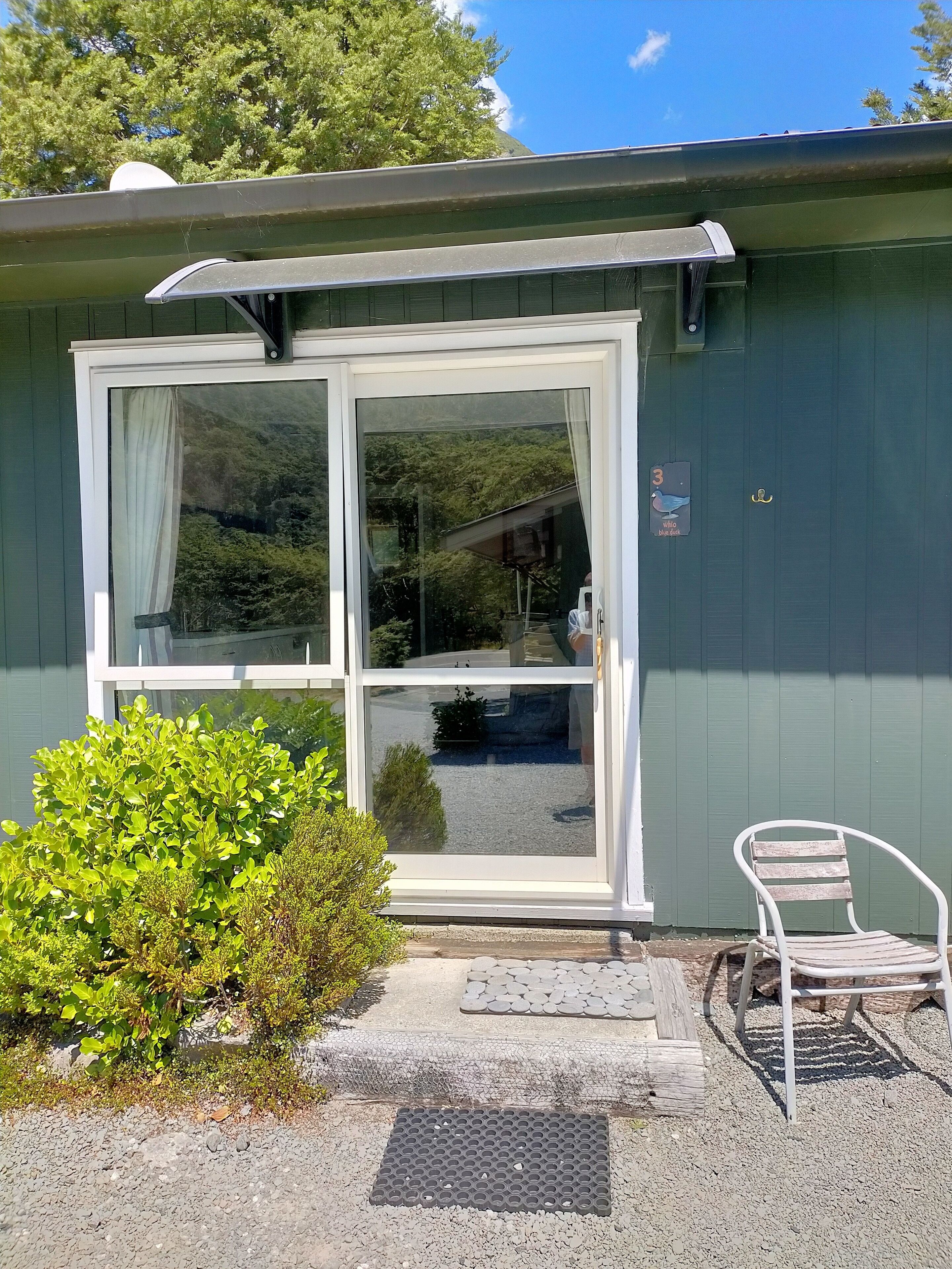 A small building with a large window, a door, and a small porch area.