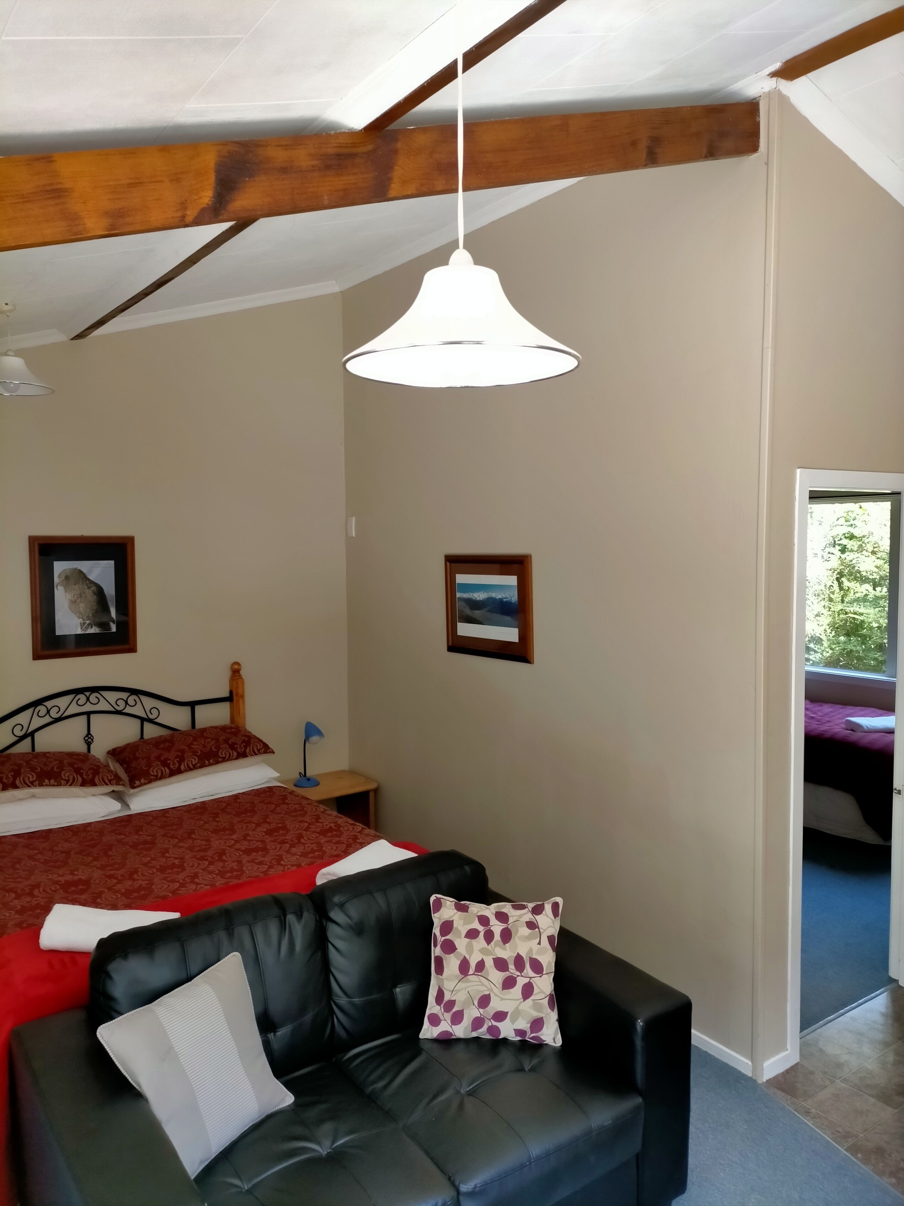 Un dormitorio con una cama, un sofá, un ventilador de techo y dos cuadros en la pared.
