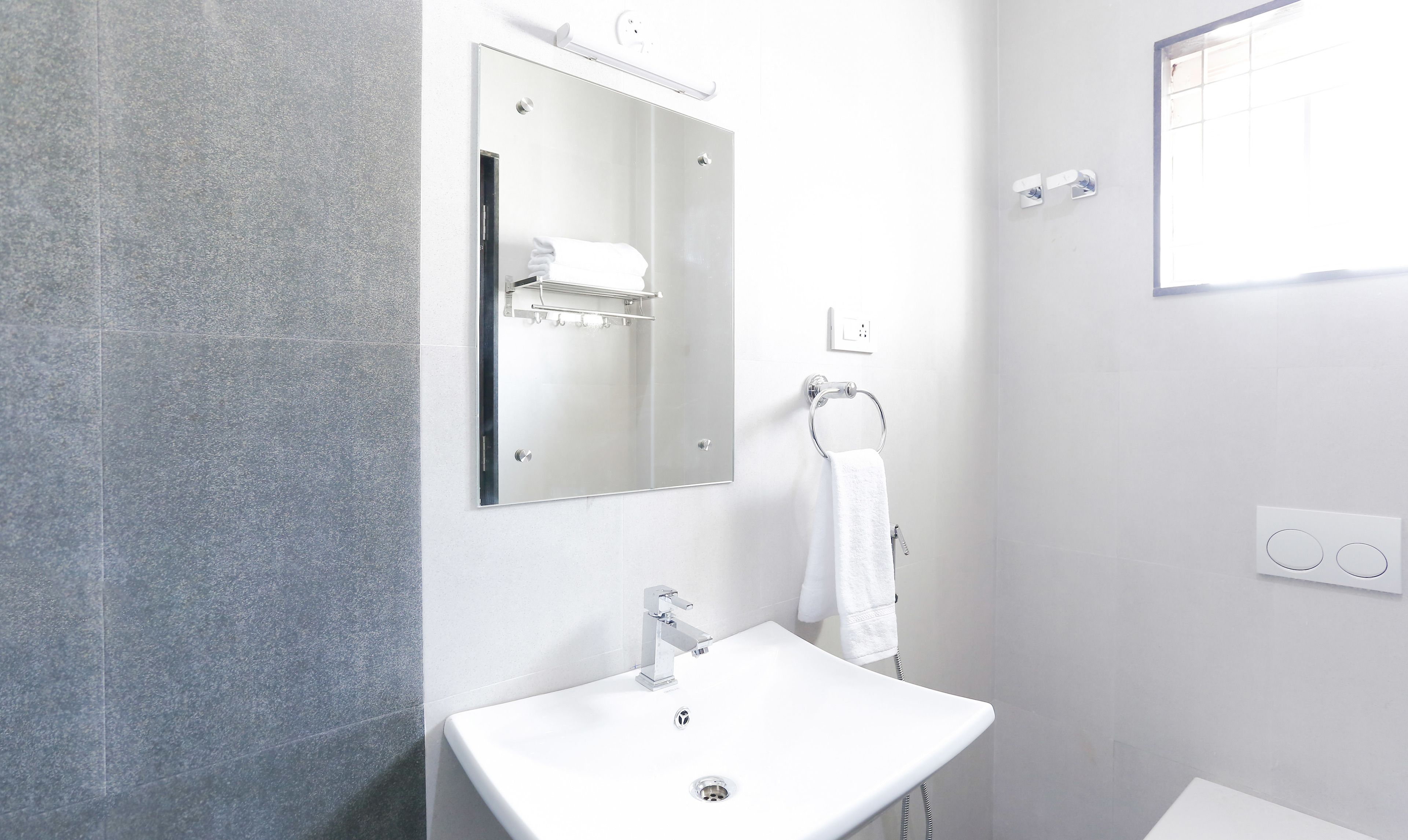 A modern bathroom with a white sink, a mirror, and a towel rack.
