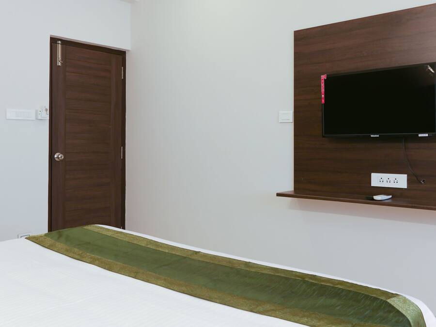 Ein Schlafzimmer mit einem Bett, einem Holzschrank, einem wandmontierten Fernseher und einer Steckdose.