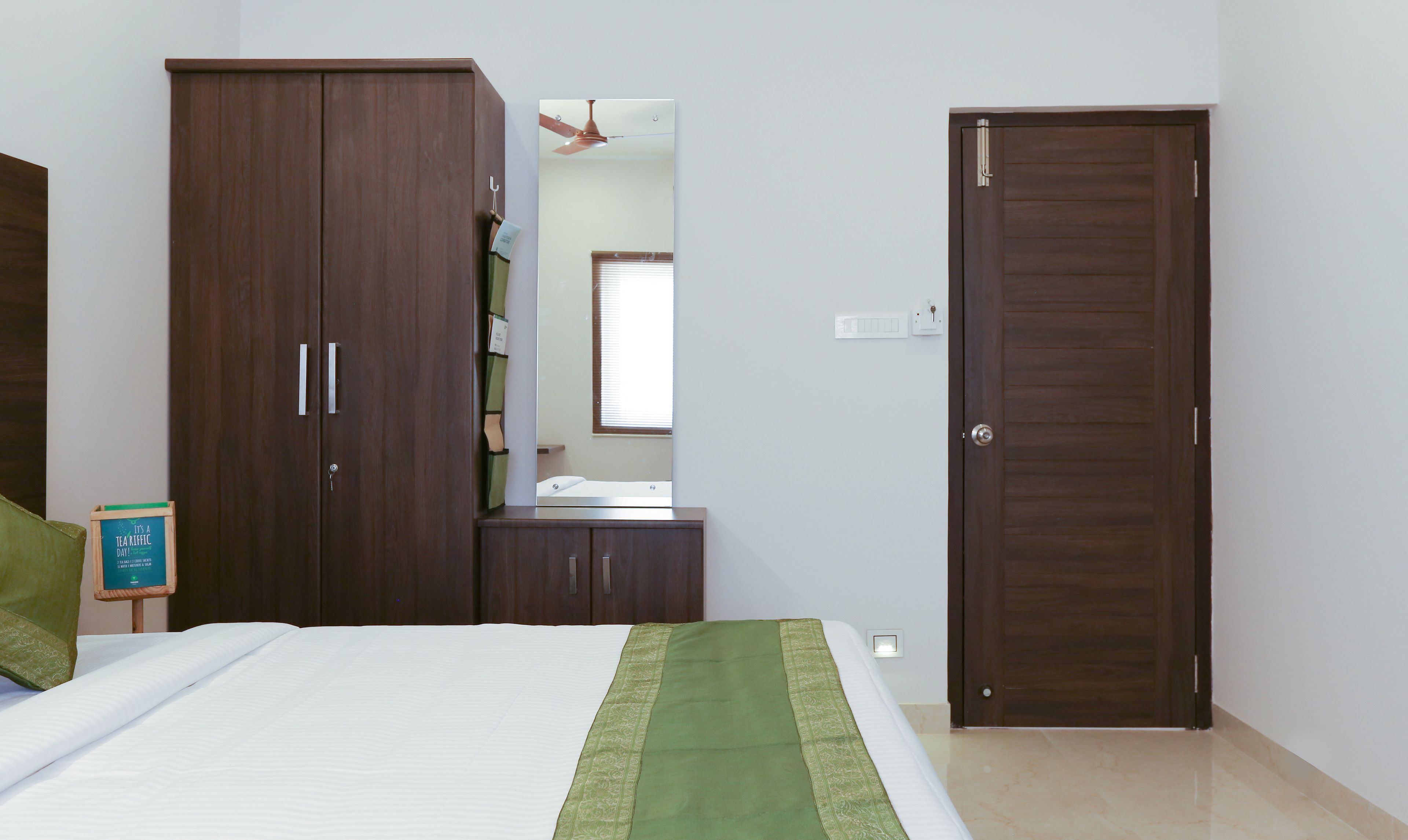 A bedroom with a bed, a wardrobe, a mirror, and a door.
