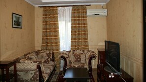 Una sala de estar con papel tapiz estampado, un sofá, un televisor y un control remoto.