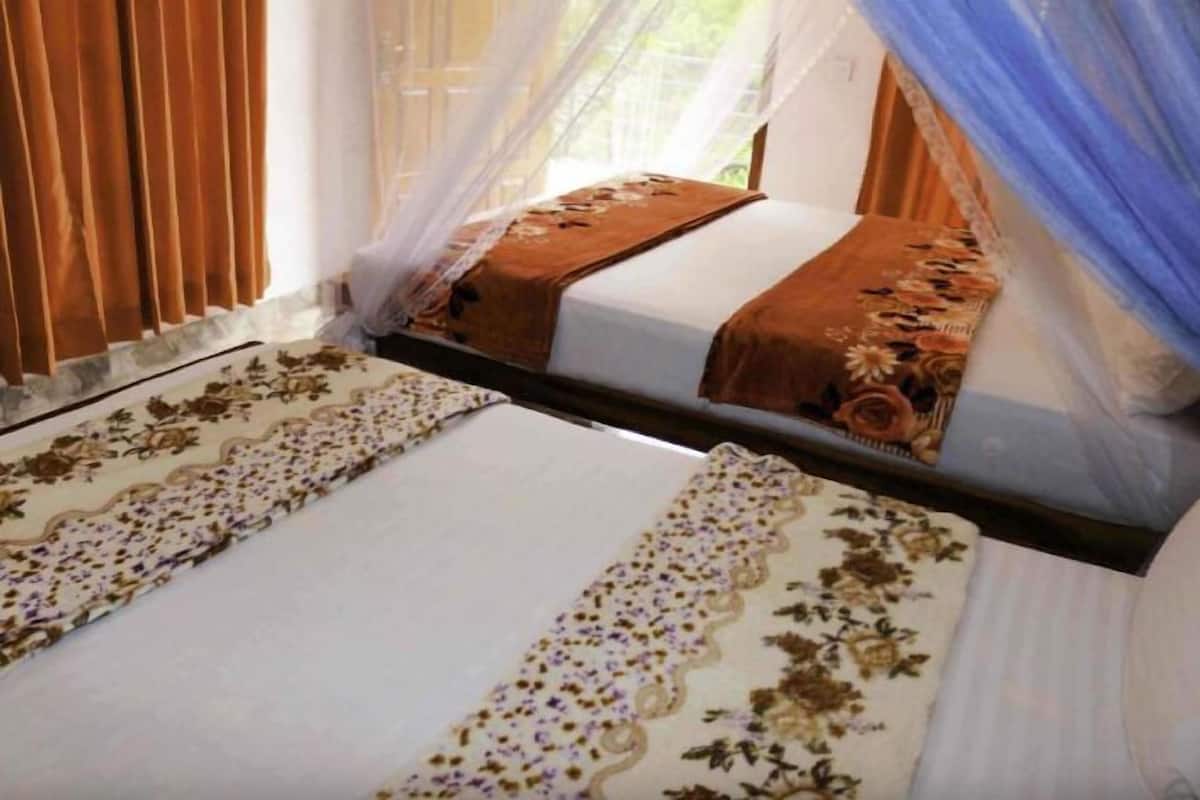A bed with a canopy, a floral-patterned bedspread, and a window with blinds.