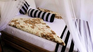 Una cama con una colcha estampada, almohadas a rayas y un dosel.