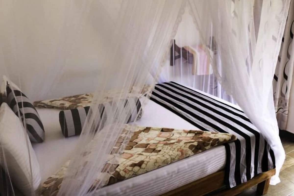 A bed with a striped bedspread, a patterned pillow, and a mosquito net.