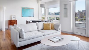 A modern living room with a white sofa, a round coffee table, and a city view through large windows. - Okendo by FeelFree Rentals (San Sebastián)