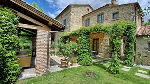 A stone building with a garden area, including a wicker sofa and potted plants. - Lovely villa with private pool, located in close distance to Cortona  (Ossaia)