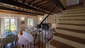 A spacious living area with a staircase, wooden beams, and a fireplace. - Lovely villa with private pool, located in close distance to Cortona  (Ossaia)